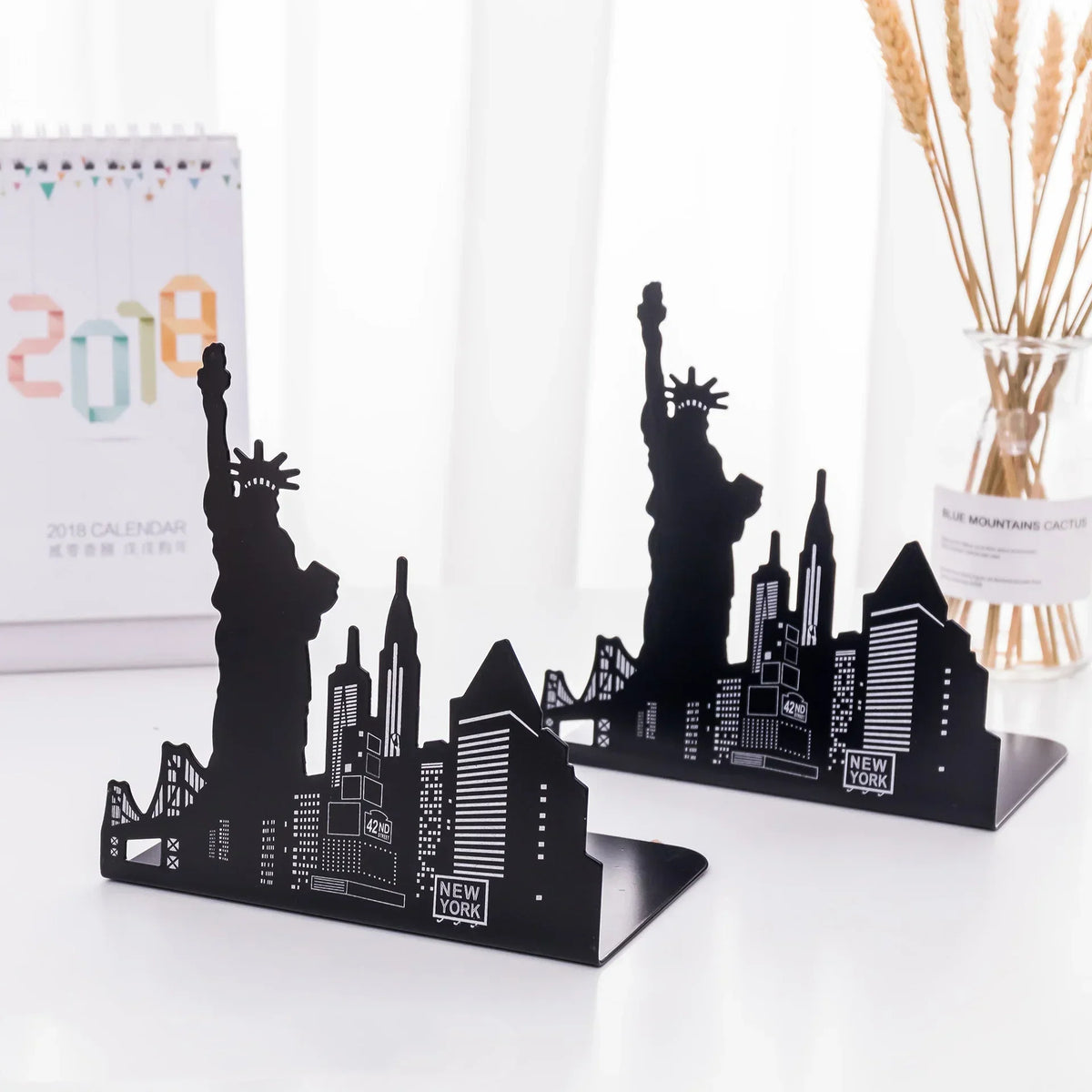 Black metal New York skyline bookends featuring Statue of Liberty, skyscrapers, and 42nd Street sign for desk decor.