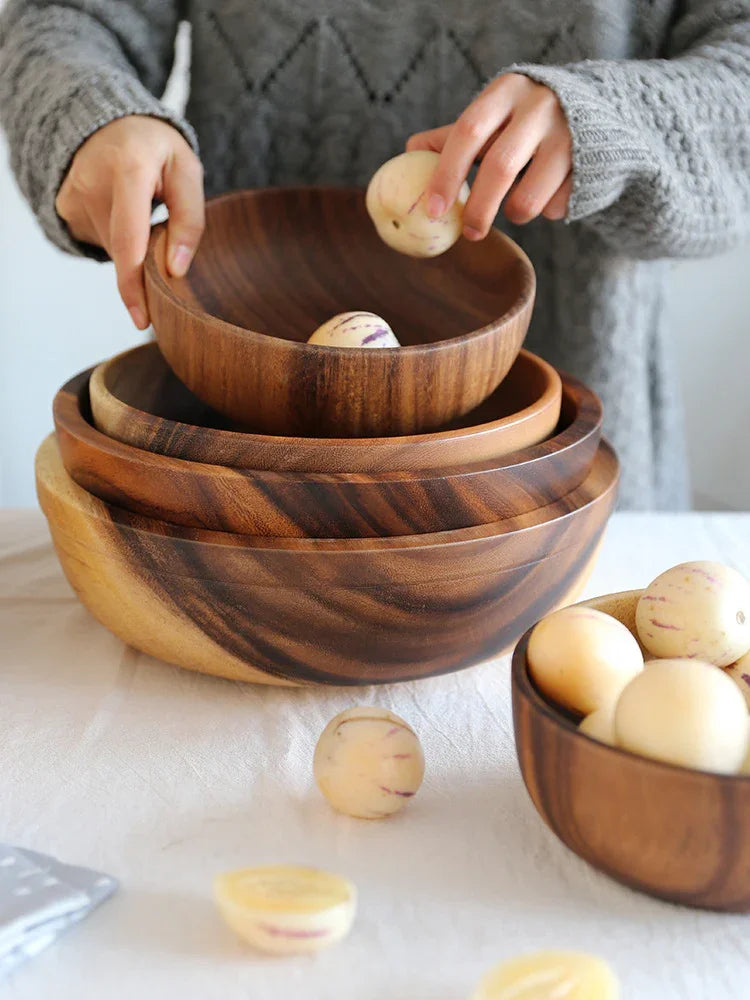 Hand placing fruit into stacked wooden bowls, natural home decor for kitchen or dining