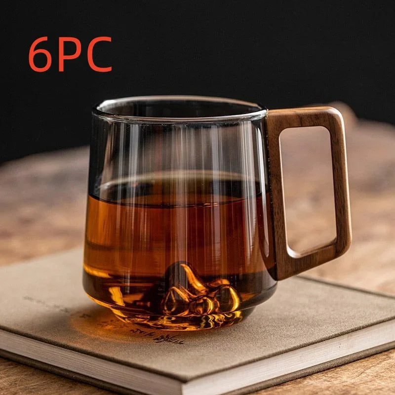 6PC glass tea mug with wooden handle, filled with amber tea, resting on book