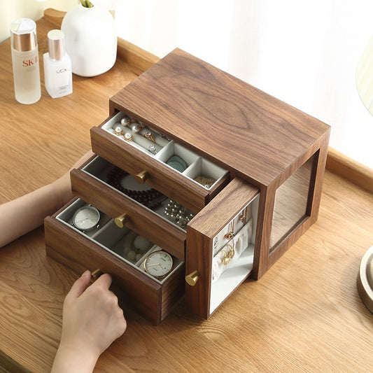 Wooden jewelry box with open drawers displaying watches and accessories on a desk