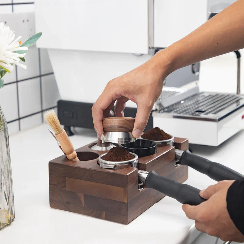 Barista using wooden coffee tamping station with portafilters and espresso machine