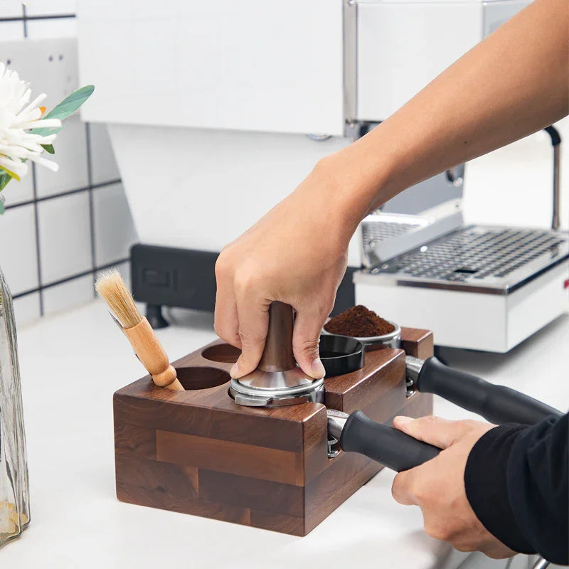 Hand tamping espresso grounds using a wooden coffee station setup in a modern kitchen