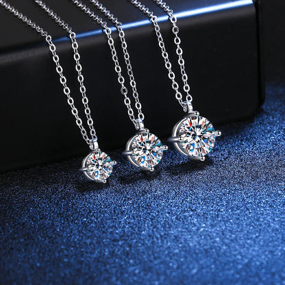 Three silver necklaces with round, sparkling crystal pendants displayed on a blue surface.