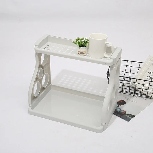 White 2-tier plastic shelf with cup holders, holding mug and small plant, ideal for kitchen or desk organization