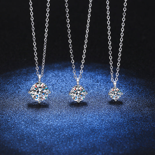 Three silver necklaces with round solitaire crystal pendants on a blue textured surface