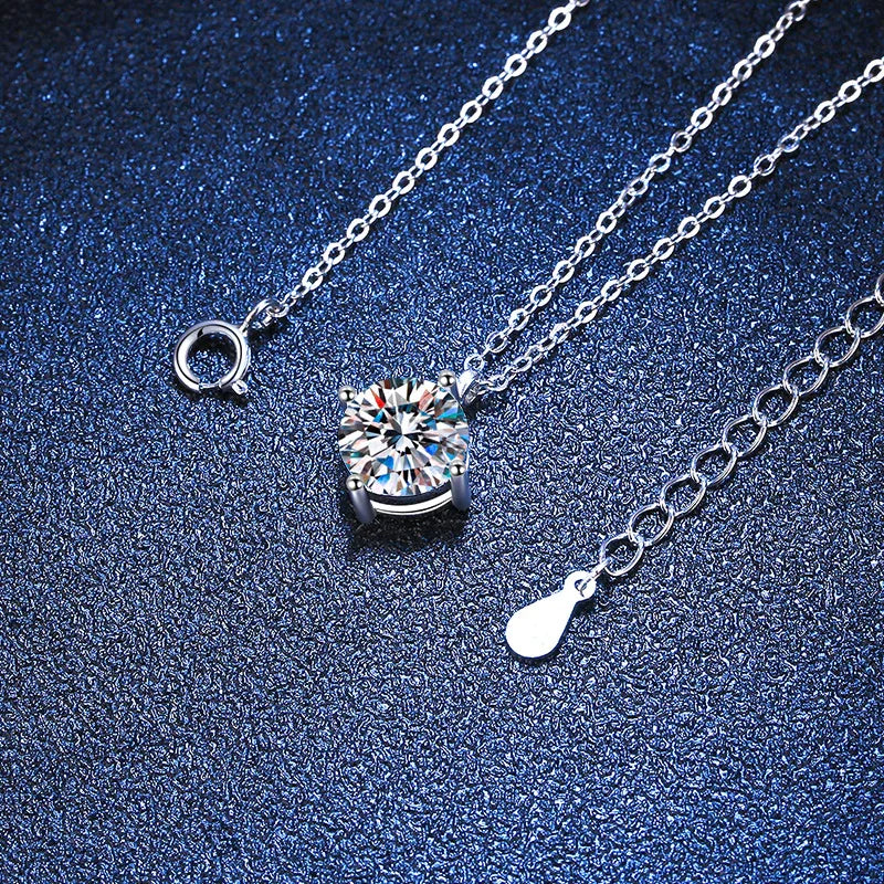 Silver chain necklace with round solitaire crystal pendant on textured blue background