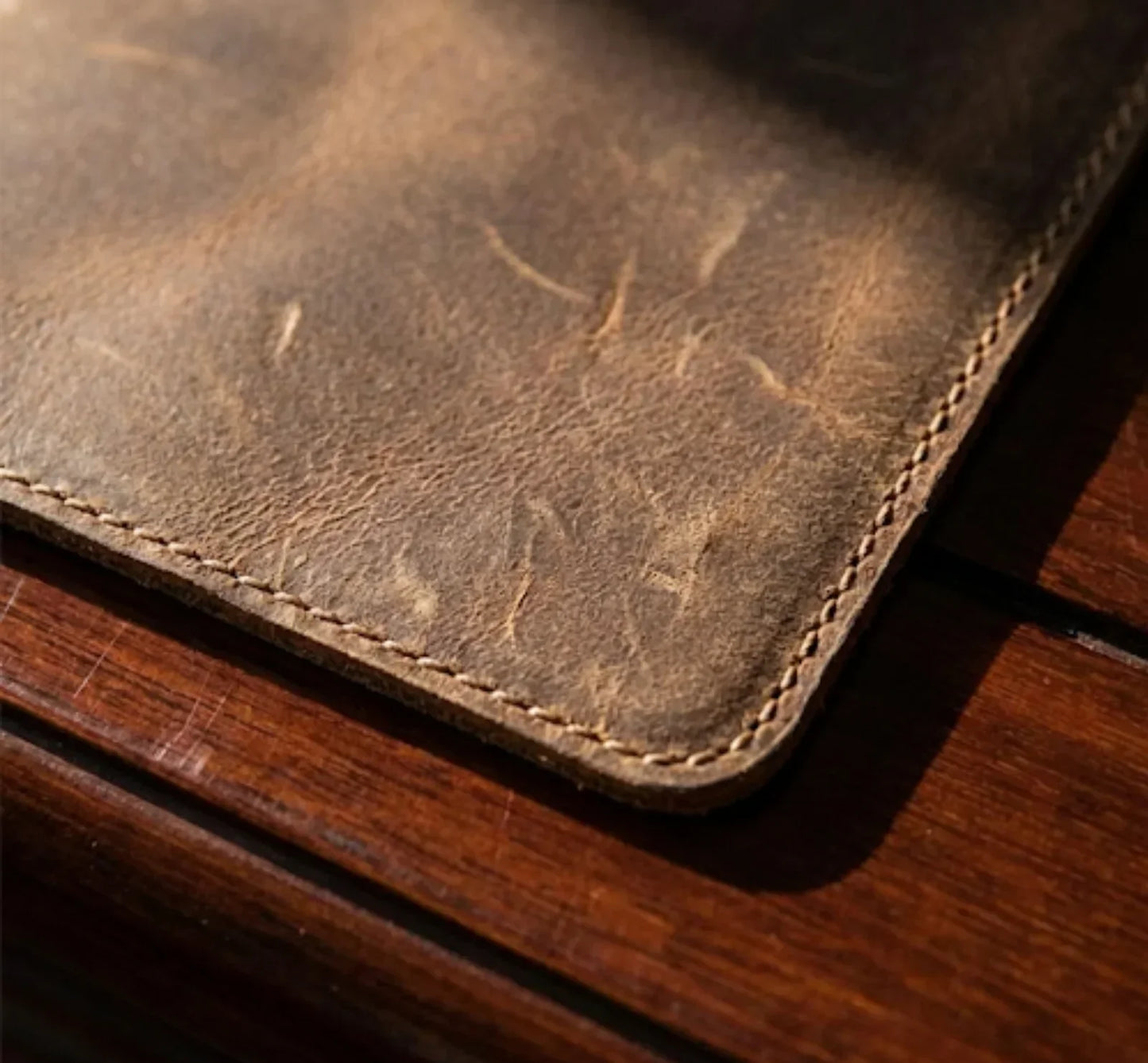 Close-up of rustic brown leather surface with visible stitching on wooden table