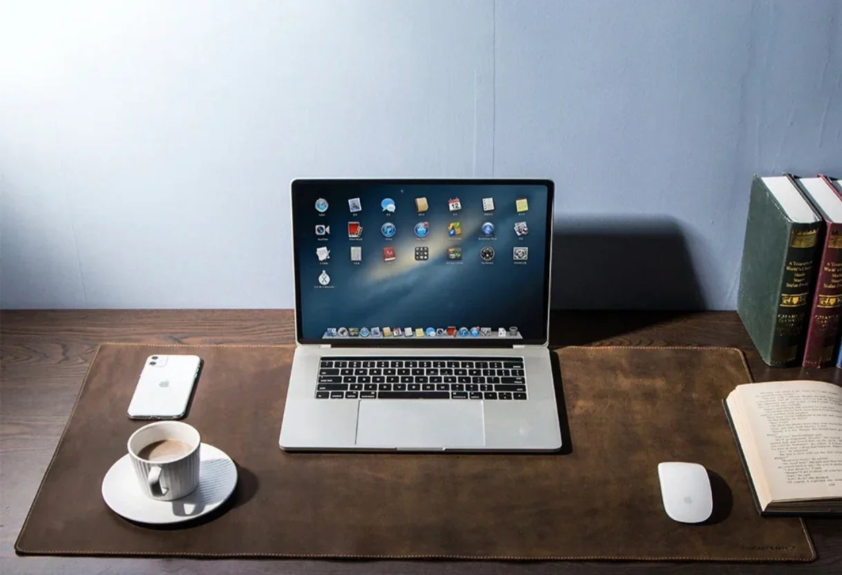 Modern workspace with laptop, smartphone, coffee cup, books, and desk mat