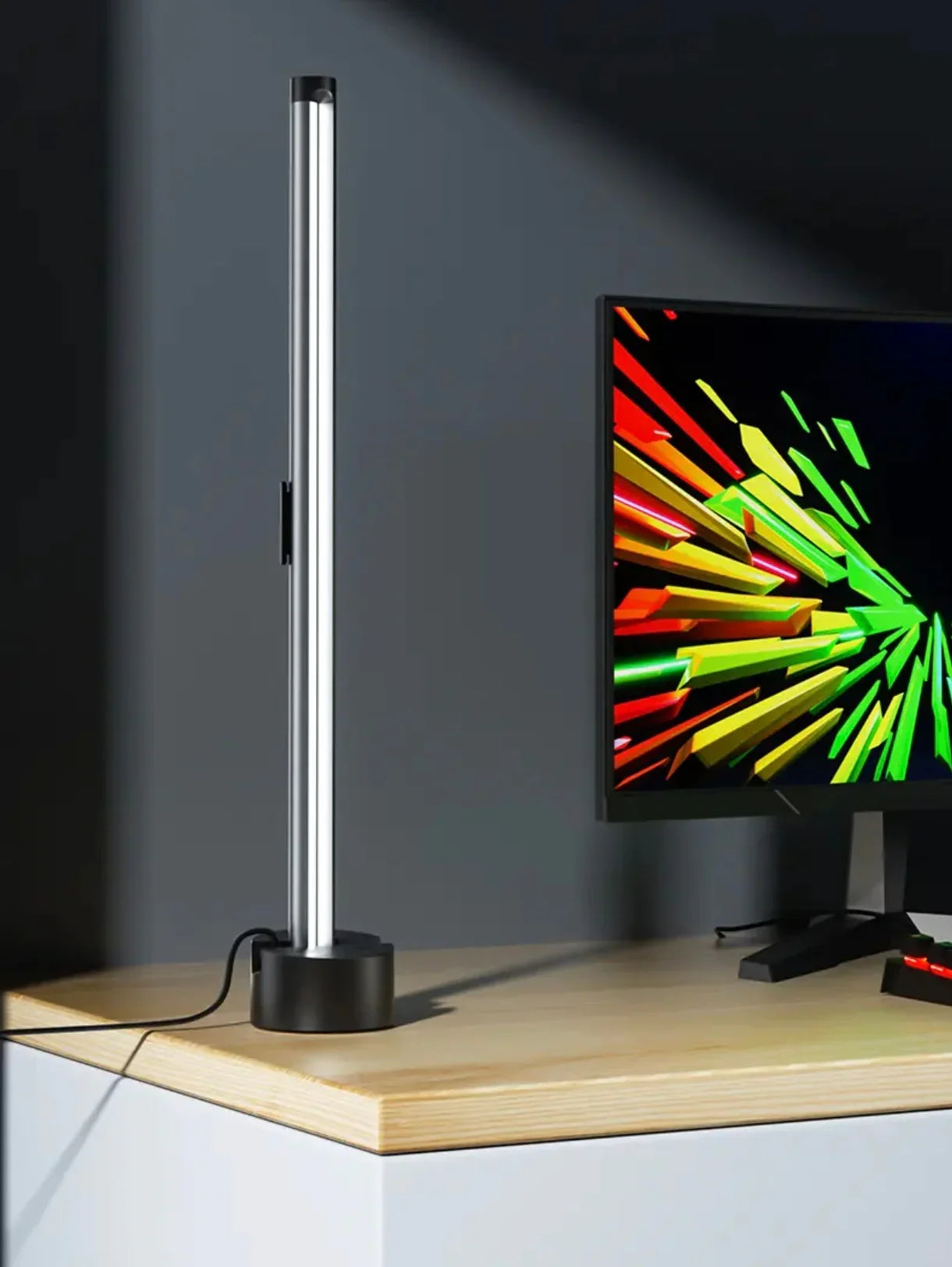Modern LED desk lamp with cylindrical design on a wooden office desk beside a computer monitor