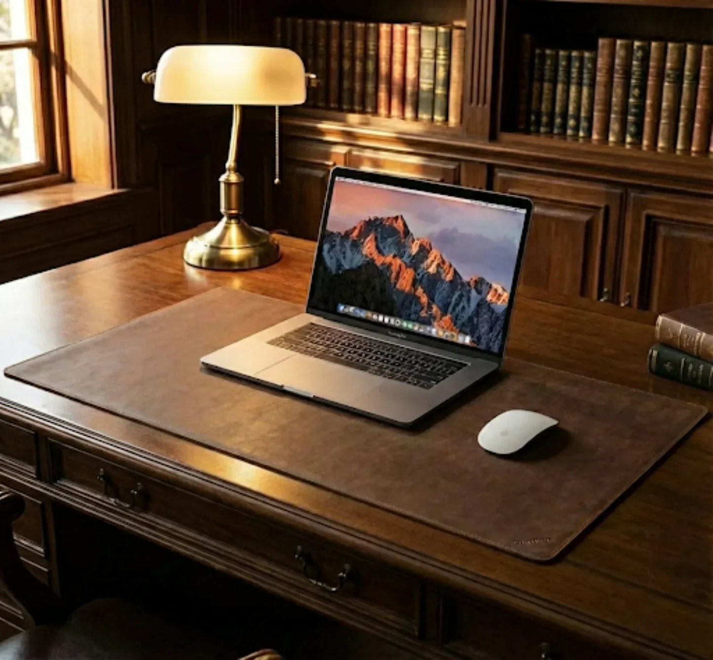 Elegant home office desk with laptop, mouse, desk mat, books and table lamp